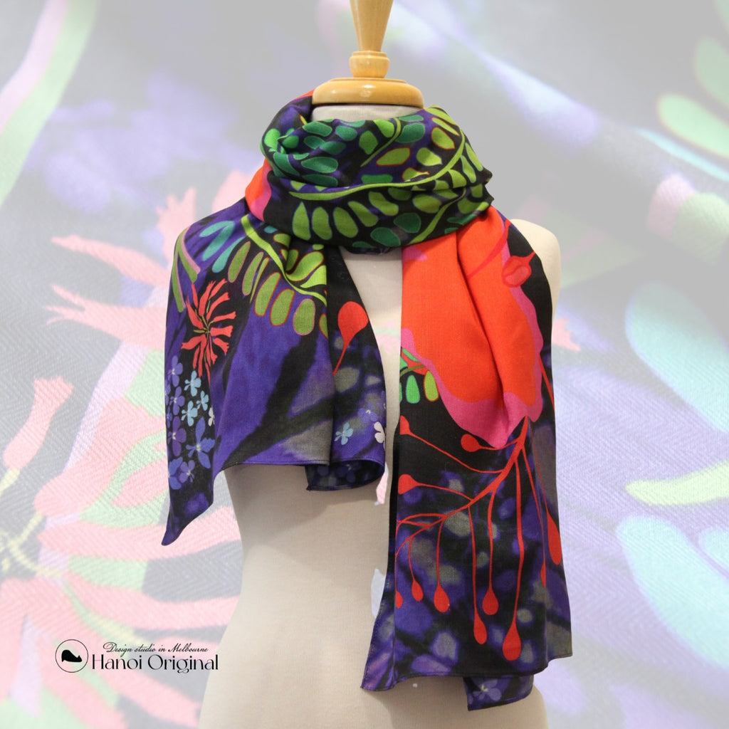 Scarf wraps around a mannequin. The scarf features a big red Royal Flame flower with blue labelio flowers