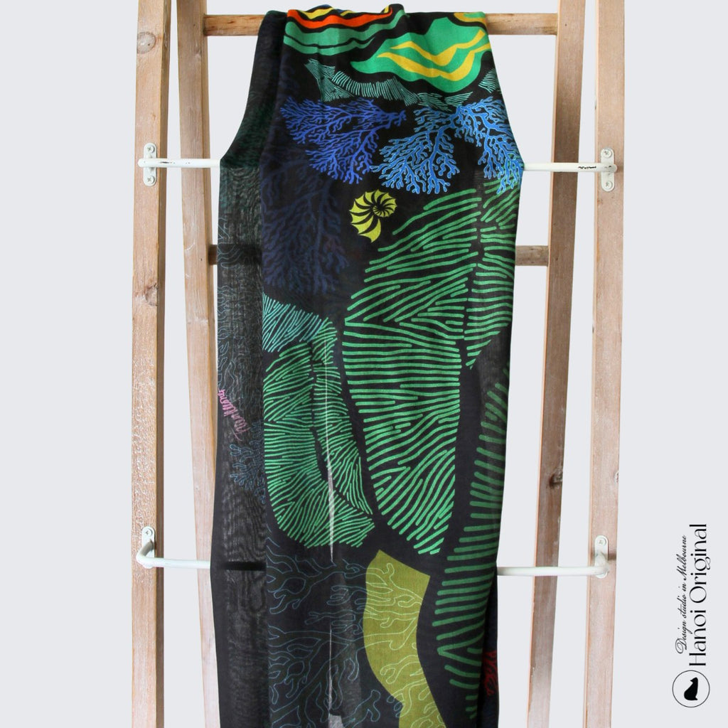 a scarf of blue and green colours featuring the underwater word with snail and coral